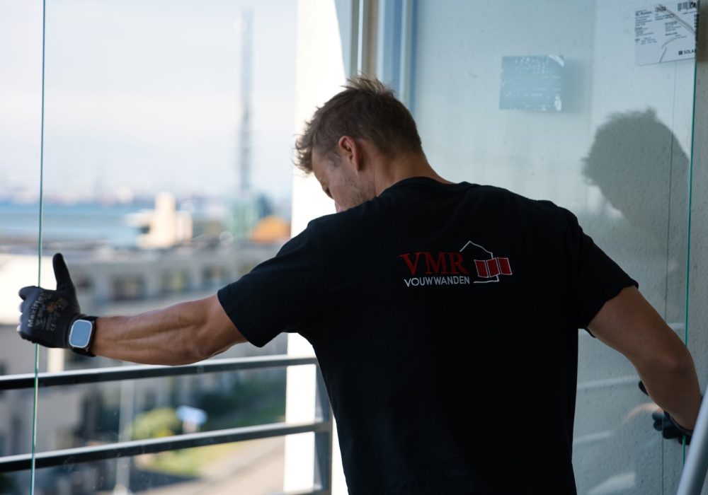 VMR-Vouwwanden-4 Detailshot van man die een groot glazen paneel in zijn handen heeft
