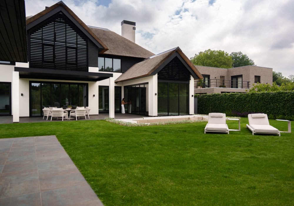 VMR-Vouwwanden-tuin-aanbouw 1 Panoramische foto van de luxe villa waar de vrouw de vouwwand aan het sluiten is