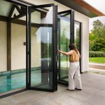 Buitenaanzicht van een luxe villa met grote glazen vouwwanden die uitkijken op het binnenzwembad