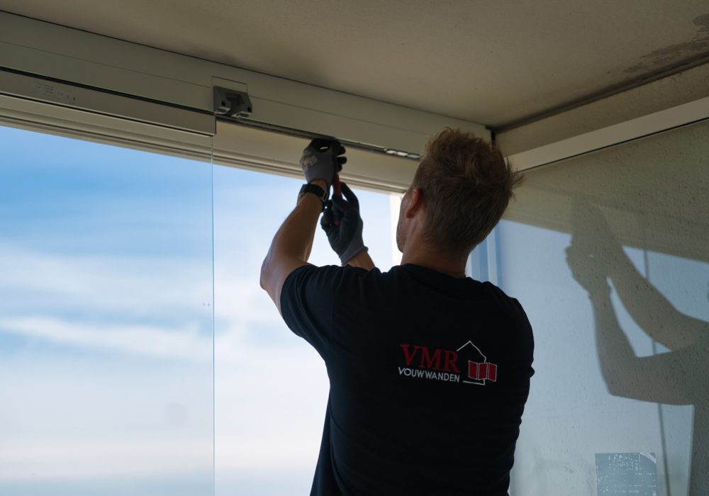 VMR-vouwwanden-6 Detailshot van man die balkonbeglazing aan het bevestigen is