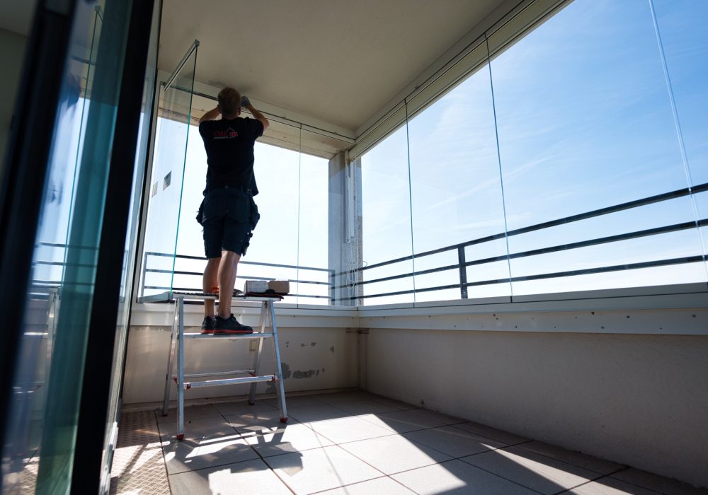 VMR-vouwwanden-8 Zijaanzicht van man die balkonbeglazing aan het monteren is