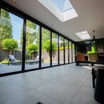 Blik van binnenuit door een gesloten glazen vouwwand naar de tuin