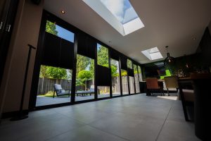 Blik van binnenuit de uitbouw met screens naar beneden voor de glazen vouwwand