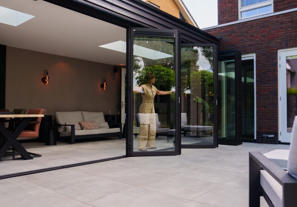 Vouwwand-zonwering-utrecht-3 Solarlux vouwwand wordt door vrouw geopend van binnenuit